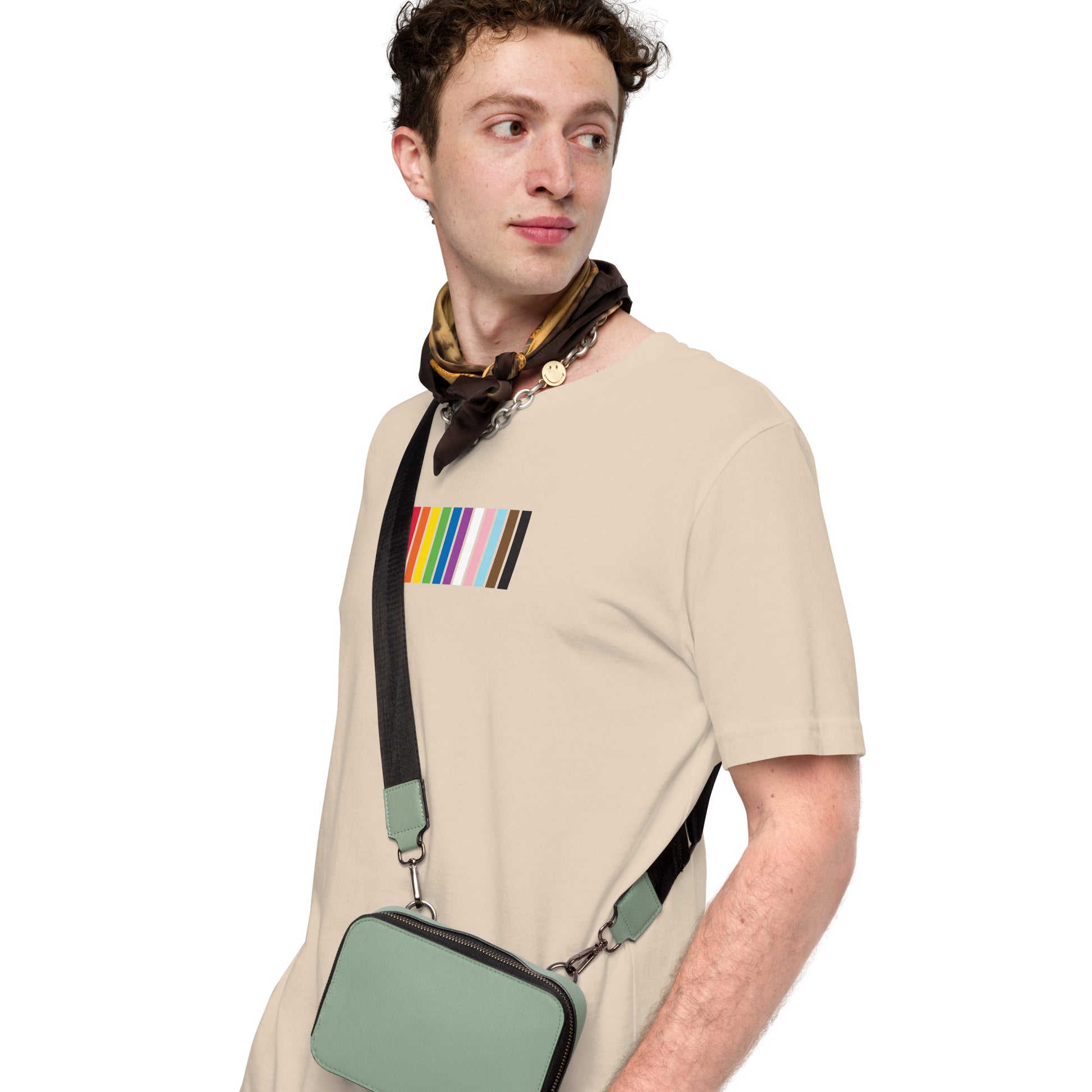 A man wearing a beige t-shirt with a colorful striped design on the front representing the LGBTQ+ community.