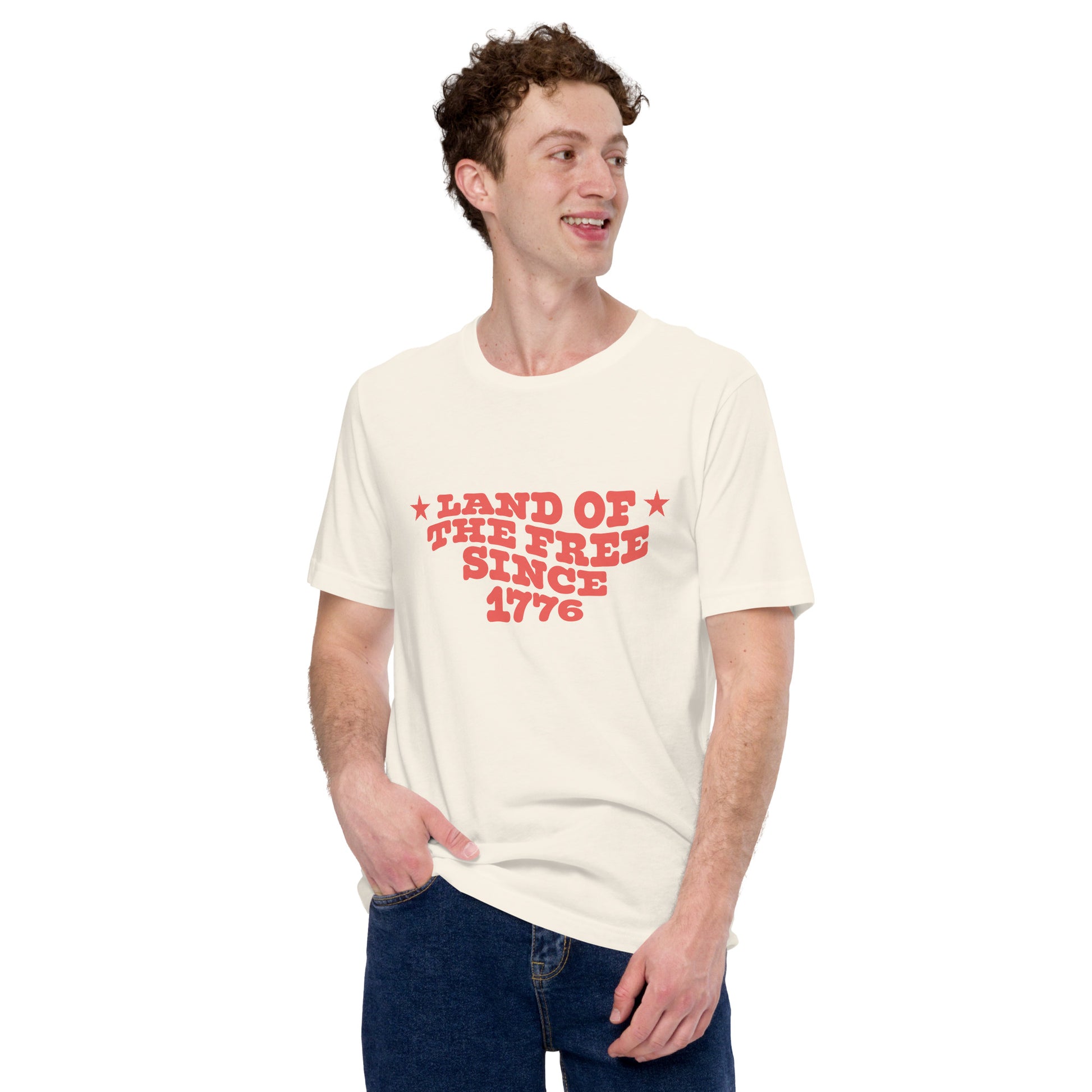 Man wearing a beige t-shirt with red text that says “LAND OF THE FREE SINCE 1776.”