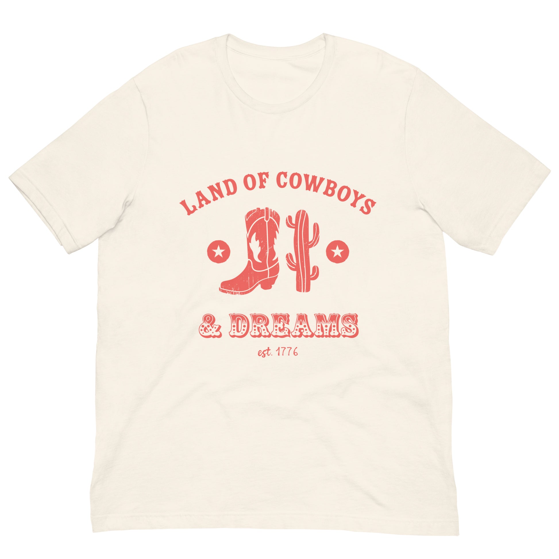 Beige t-shirt with a red graphic featuring a cowboy boot, cactus, and text that says “Land of the Cowboys and Dreams est. 1776.”